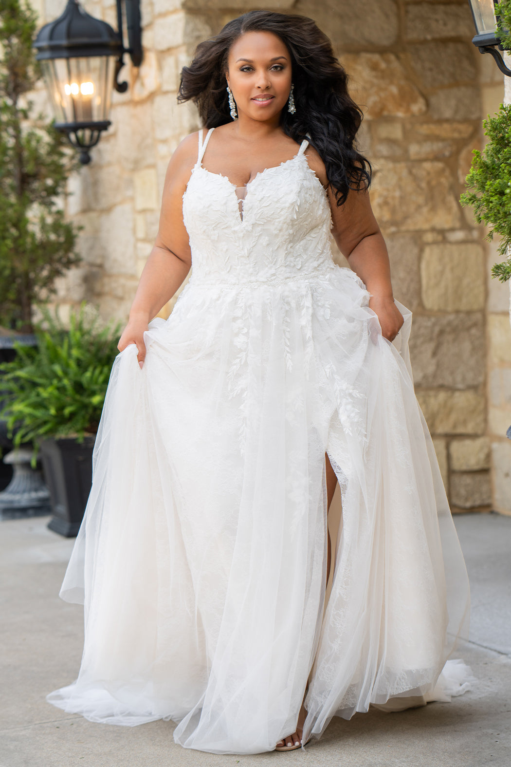 Michelle Bridal MB2613 shown in Ivory. 
Beaded double spaghetti straps, v-neckline, natural waistline. 3D floral appliques, soft bridal tulle, satin lining. A-Line skirt with left leg slit. Scoop back and center back zipper. 