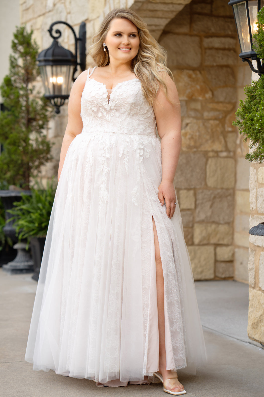 Michelle Bridal MB2613 shown in Rosewater. 
Beaded double spaghetti straps, v-neckline, natural waistline. 3D floral appliques, soft bridal tulle, satin lining. A-Line skirt with left leg slit. Scoop back and center back zipper. 