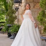 Michelle Bridal MB2615 shown in Ivory. 
Long sleeves covered in large organza appliques, v-neckline, 3 inch waistband. A-line skirt, Soft bridal tulle, large organa appliques, lightweight satin lining. V-Back, Long train and center back zipper. 