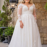 Michelle Bridal MB2615 shown in Ivory. 
Long sleeves covered in large organza appliques, v-neckline, 3 inch waistband. A-line skirt, Soft bridal tulle, large organa appliques, lightweight satin lining. V-Back, Long train and center back zipper. 