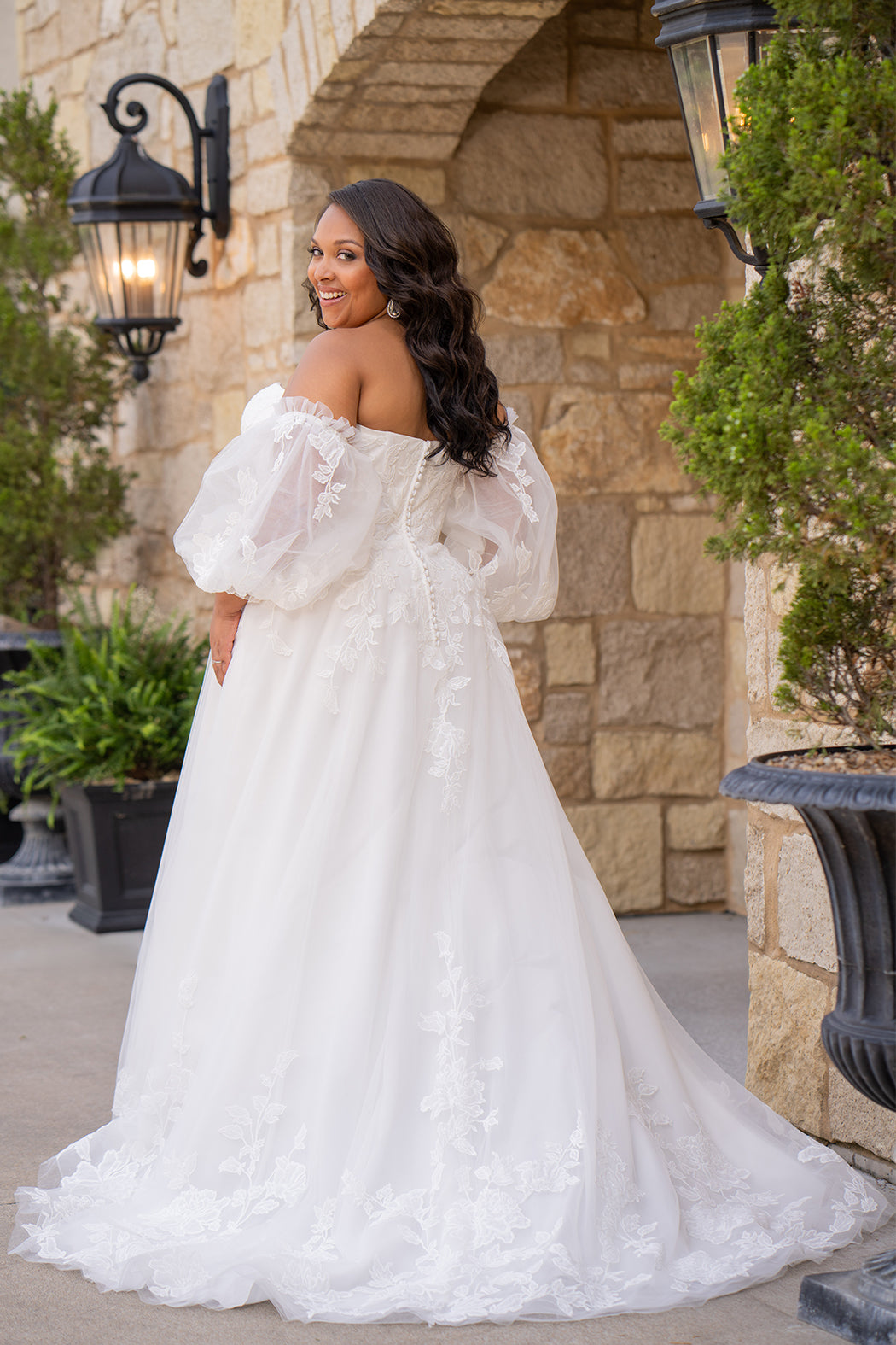 Michelle Bridal MB2618 shown in Ivory. 

Strapless sweetheart ballgown. Soft bridal tulle, floral lace appliques, lightweight satin lining. Natural waistline, A-Line skirt. Bicep optional puff sleeves. Straight across back, center back zipper, train and covered buttons. 