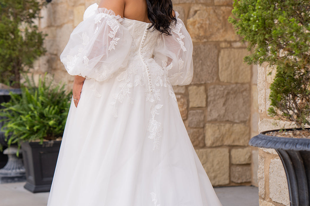 Michelle Bridal MB2618 shown in Ivory. 

Strapless sweetheart ballgown. Soft bridal tulle, floral lace appliques, lightweight satin lining. Natural waistline, A-Line skirt. Bicep optional puff sleeves. Straight across back, center back zipper, train and covered buttons. 