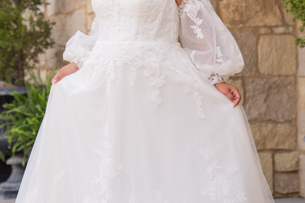 Michelle Bridal MB2618 shown in Ivory. 

Strapless sweetheart ballgown. Soft bridal tulle, floral lace appliques, lightweight satin lining. Natural waistline, A-Line skirt. Bicep optional puff sleeves. Straight across back, center back zipper, train and covered buttons. 