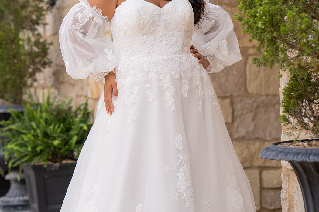 Michelle Bridal MB2618 shown in Ivory. 

Strapless sweetheart ballgown. Soft bridal tulle, floral lace appliques, lightweight satin lining. Natural waistline, A-Line skirt. Bicep optional puff sleeves. Straight across back, center back zipper, train and covered buttons. 