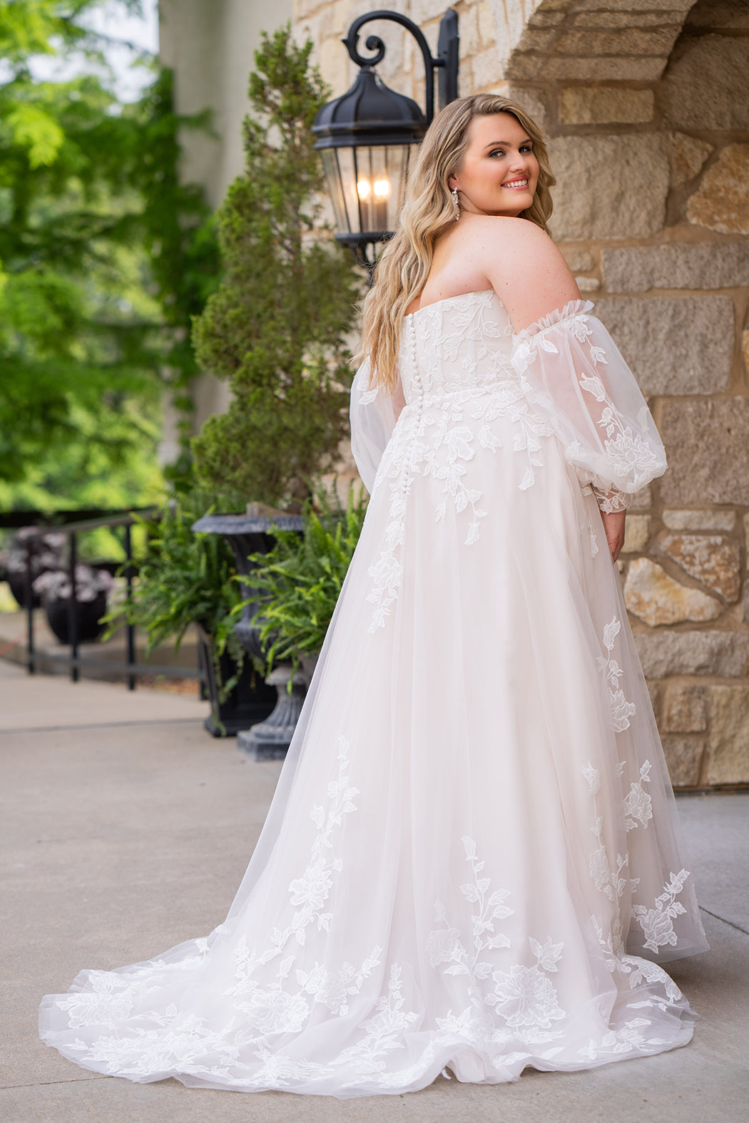 Michelle Bridal MB2618 shown in Latte. 

Strapless sweetheart ballgown. Soft bridal tulle, floral lace appliques, lightweight satin lining. Natural waistline, A-Line skirt. Bicep optional puff sleeves. Straight across back, center back zipper, train and covered buttons. 