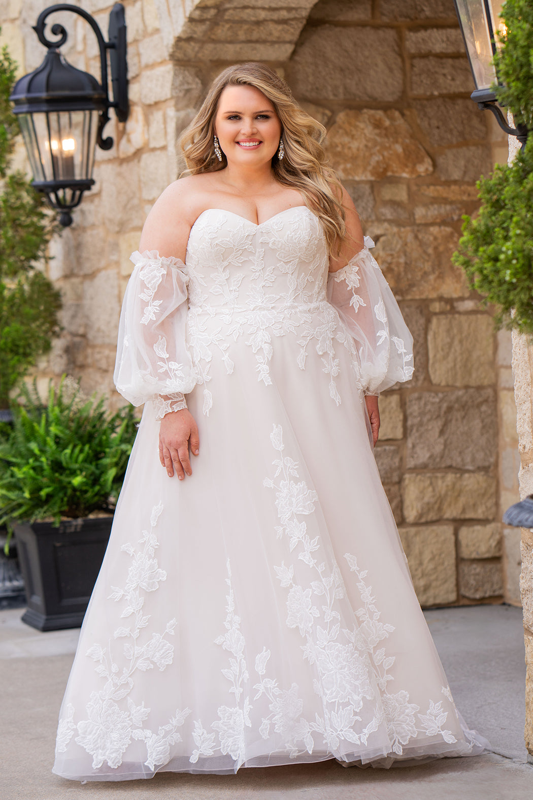 Michelle Bridal MB2618 shown in Latte. 

Strapless sweetheart ballgown. Soft bridal tulle, floral lace appliques, lightweight satin lining. Natural waistline, A-Line skirt. Bicep optional puff sleeves. Straight across back, center back zipper, train and covered buttons. 