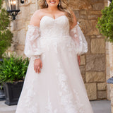 Michelle Bridal MB2618 shown in Sand. 

Strapless sweetheart ballgown. Soft bridal tulle, floral lace appliques, lightweight satin lining. Natural waistline, A-Line skirt. Bicep optional puff sleeves. Straight across back, center back zipper, train and covered buttons. 