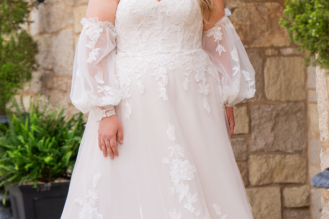 Michelle Bridal MB2618 shown in Sand. 

Strapless sweetheart ballgown. Soft bridal tulle, floral lace appliques, lightweight satin lining. Natural waistline, A-Line skirt. Bicep optional puff sleeves. Straight across back, center back zipper, train and covered buttons. 