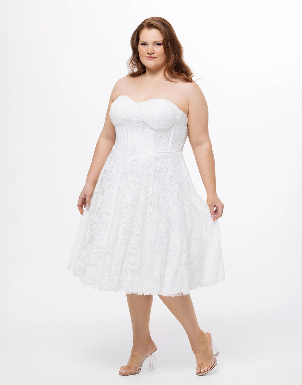 Woman wearing a white, lace, strapless dress on a white background