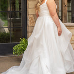 Woman in a white wedding dress standing outdoors near a stone wall.

Sydney's Closet style SC5359 pleated organza bridal gown with tiered ball gown skirt.