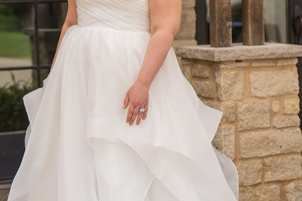 Woman in a white wedding dress standing outdoors near a stone wall.

Sydney's Closet style SC5359 pleated organza bridal gown with tiered ball gown skirt.