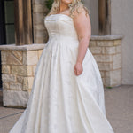Plus size floral brocade wedding dress style SC5263 from designer Sydney's Closet.  Strapless, straight across neckline with folded cuff detail. Full A-line skirt with box pleats, crinoline and pockets. Long train and center back zipper. 