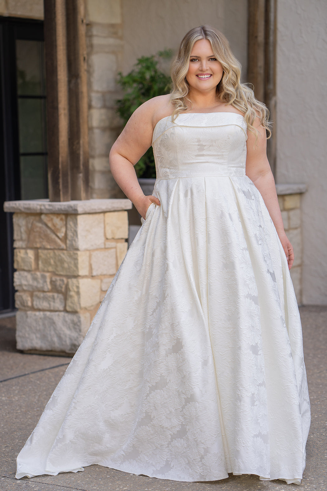 Plus size floral brocade wedding dress style SC5263 from designer Sydney's Closet.  Strapless, straight across neckline with folded cuff detail. Full A-line skirt with box pleats, crinoline and pockets. Long train and center back zipper. 