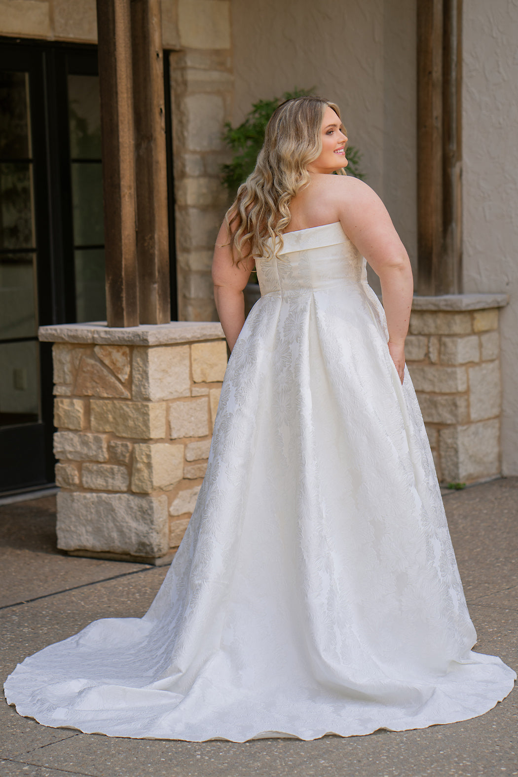 Plus size floral brocade wedding dress style SC5263 from designer Sydney's Closet.  Strapless, straight across neckline with folded cuff detail. Full A-line skirt with box pleats, crinoline and pockets. Long train and center back zipper. 