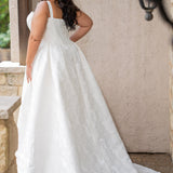 Plus size brocade wedding gown with square neckline and wide straps.  Exposed corset boning and basque waistline make for an elogating fit.  Gathered A-line skirt with pockets and a train add a traditional touch.  Sydney's Closet SC5363 is available in Buttercream. 