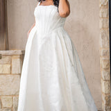 Plus size brocade wedding gown with square neckline and wide straps.  Exposed corset boning and basque waistline make for an elogating fit.  Gathered A-line skirt with pockets and a train add a traditional touch.  Sydney's Closet SC5363 is available in Buttercream. 