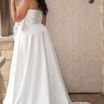 Strapless plus size satin wedding dress with pleated bodice and oversizes bow with pearl embelished details.  Natural waistline with full A-line skirt and pockets.  Sydney's Closet style SC5363 available in ivory. 