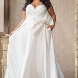 Strapless plus size satin wedding dress with pleated bodice and oversizes bow with pearl embelished details.  Natural waistline with full A-line skirt and pockets.  Sydney's Closet style SC5363 available in ivory. 