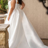 Sydney's Closet style SC5365 - Ivory bridal Mikado satin wedding dress with square neckline, wide straps with detachable bows, natural waistline, full A-line skirt with box pleats, pockets and a long train. 