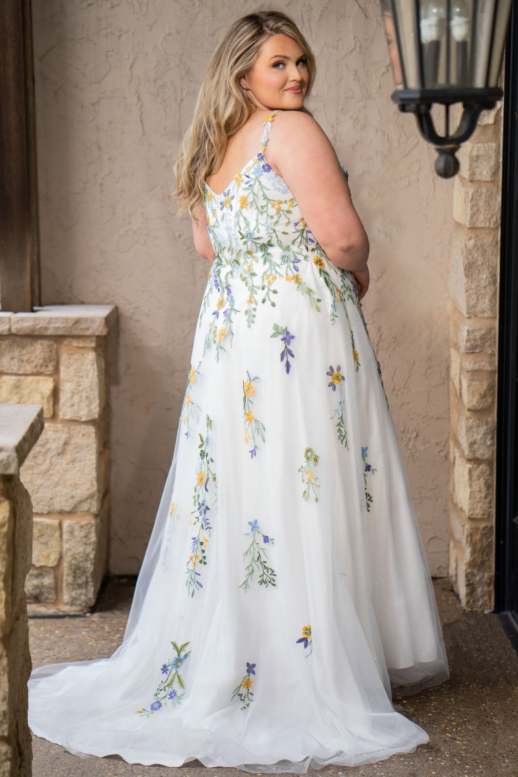 Sydney's Closet SC5371 plus size wedding dress.  Multi-colored floral lace on ivory tulle. Sexy plunging V-neckline with exposed corset boning.  Basque waistline on A-line skirt with slit and long train with lace details. Perfect for the unique, trendy bride.