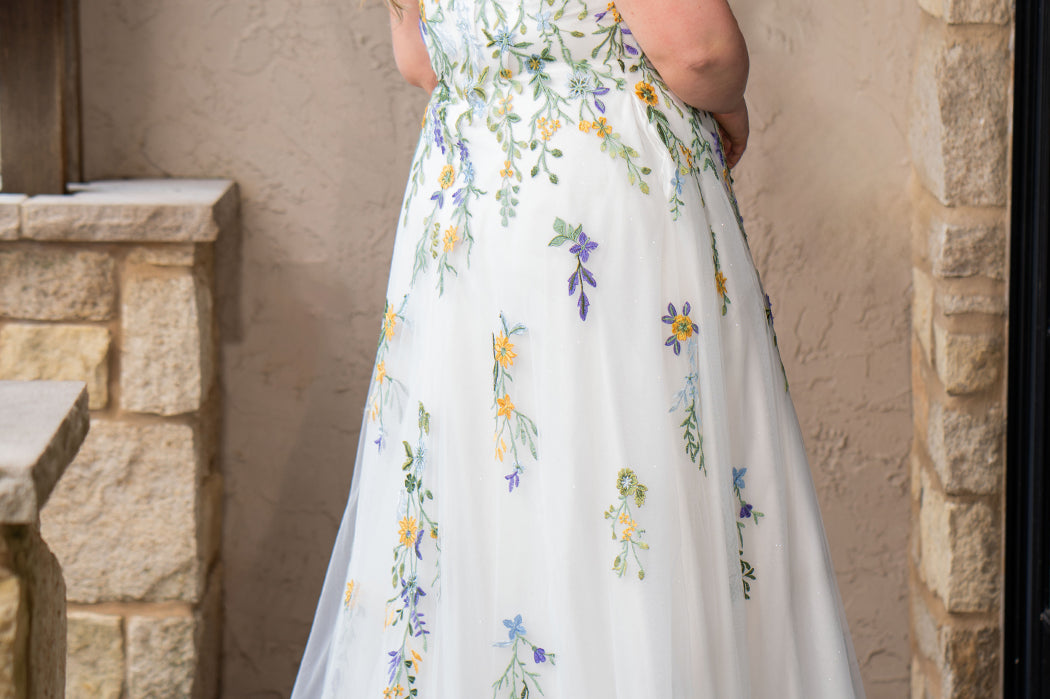 Sydney's Closet SC5371 plus size wedding dress.  Multi-colored floral lace on ivory tulle. Sexy plunging V-neckline with exposed corset boning.  Basque waistline on A-line skirt with slit and long train with lace details. Perfect for the unique, trendy bride.