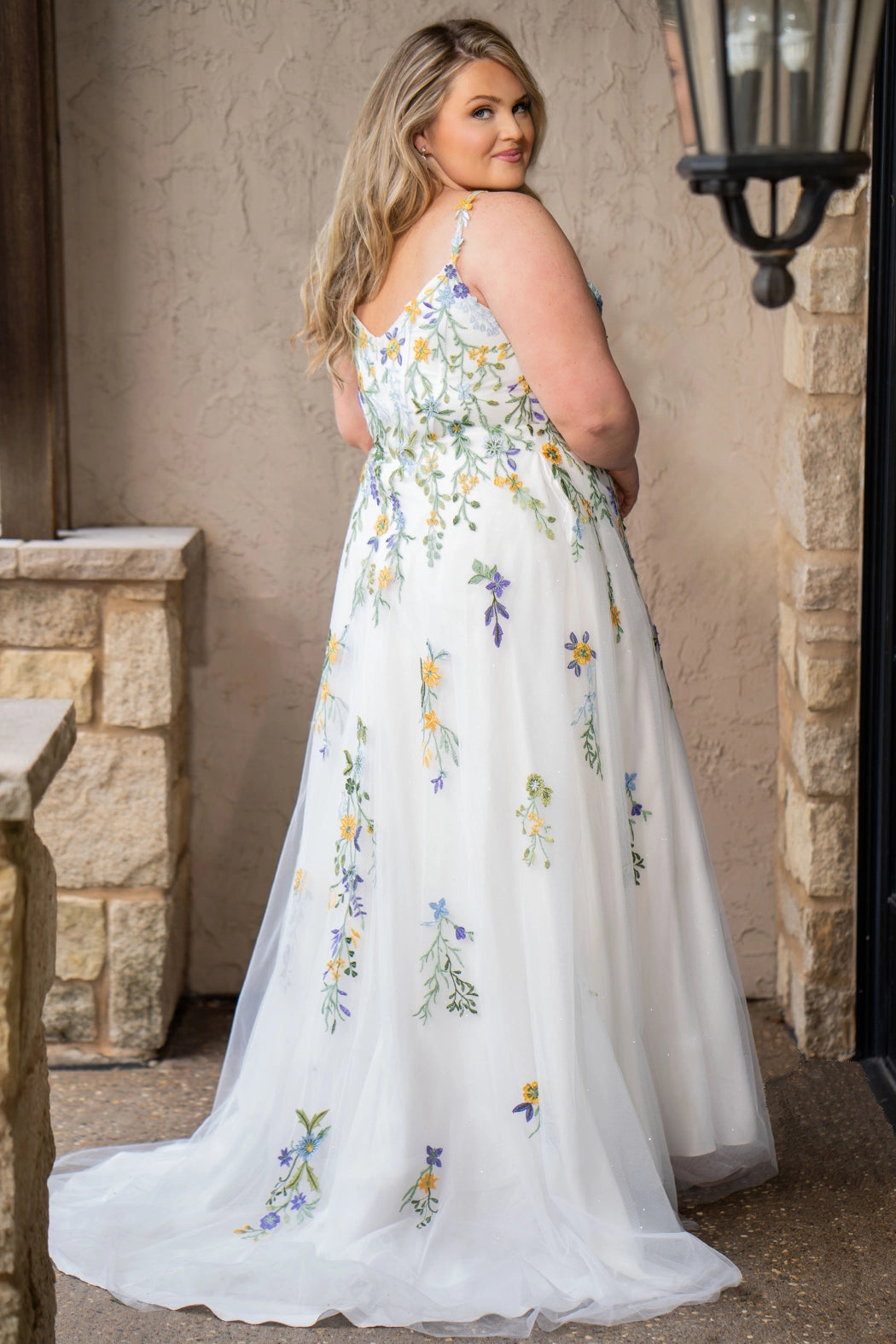 Sydney's Closet SC5371 plus size wedding dress.  Multi-colored floral lace on ivory tulle. Sexy plunging V-neckline with exposed corset boning.  Basque waistline on A-line skirt with slit and long train with lace details. Perfect for the unique, trendy bride.