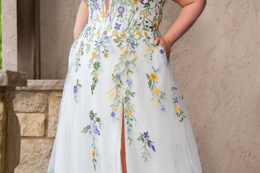 Sydney's Closet SC5371 plus size wedding dress.  Multi-colored floral lace on ivory tulle. Sexy plunging V-neckline with exposed corset boning.  Basque waistline on A-line skirt with slit and long train with lace details. Perfect for the unique, trendy bride.