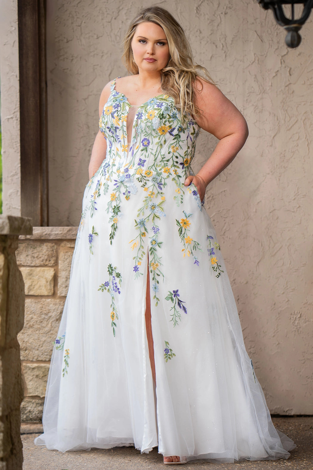 Sydney's Closet SC5371 plus size wedding dress.  Multi-colored floral lace on ivory tulle. Sexy plunging V-neckline with exposed corset boning.  Basque waistline on A-line skirt with slit and long train with lace details. Perfect for the unique, trendy bride.