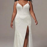 Plus-size bride wearing an elegant ivory wedding gown with a fitted silhouette, delicate spaghetti straps, and a plunging V-neckline with sheer nude inset detail. The bridal dress features allover pearls and silver stone embellishments, a defined waist, and a floor-length skirt with a thigh-high slit. She is styled with natural curls, sparkling drop earrings, and ivory pointed-toe heels, walking confidently against a neutral studio background.

Sydney's Closet SC5377