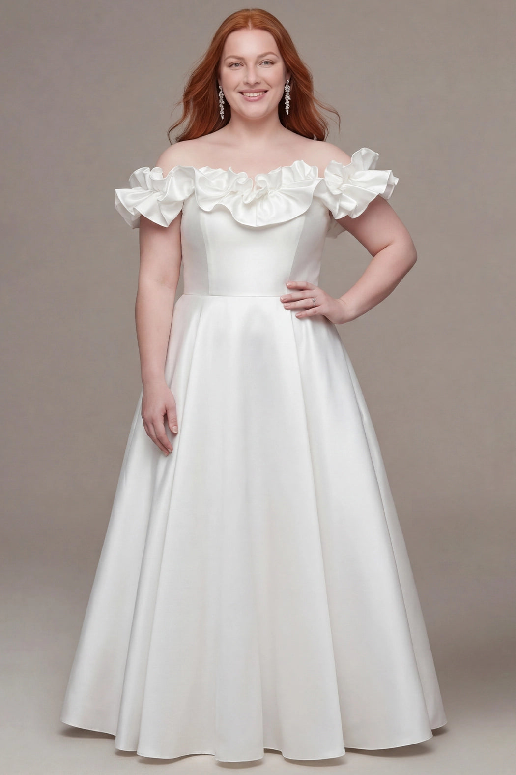 Plus-size bride wearing a timeless ivory wedding gown with an off-the-shoulder neckline adorned with dramatic ruffled sleeves and a softly structured bodice. The bridal dress features a defined waist and a classic A-line skirt that flows to the floor, creating an elegant and romantic silhouette. She is styled with long red hair, sparkling drop earrings, and a natural bridal look, posing against a neutral studio background.

Sydney's Closet SC5378