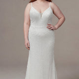 Plus-size bride wearing a fitted ivory lace wedding gown with delicate spaghetti straps, a plunging V-neckline with a sheer inset, and allover pearl-inspired beadwork. The figure-flattering silhouette contours the body with appliques on the side seams before gently flaring into a soft sweep train, creating an elegant and timeless bridal look. She is styled with long red hair and sparkling drop earrings, posing against a neutral studio background.

Sydney's Closet SC5382