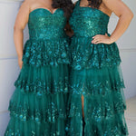 SC7398 & SC7399 duo picture outside for prom 2025. 

Strapless, sweetheart plus size gala formal ballgown. Exposed corset boning on bodice covered in lace applqiues. Tiered A-line skirt with matching lace applique hem. Style SC7398 is available in forest green, navy blue or burgundy red by Sydney's Closet. 

Plus size one-shoulder formal gala Mardi Gras gown with embroidered sequin lace appliques on bodice and on tiered A-line skirt with slit. Available in forest green. navy blue and burgundy r