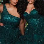 SC7398 & SC7399 duo picture with oversized candy for prom 2025. 

Strapless, sweetheart plus size gala formal ballgown. Exposed corset boning on bodice covered in lace applqiues. Tiered A-line skirt with matching lace applique hem. Style SC7398 is available in forest green, navy blue or burgundy red by Sydney's Closet. 

Plus size one-shoulder formal gala Mardi Gras gown with embroidered sequin lace appliques on bodice and on tiered A-line skirt with slit. Available in forest green. navy blue and burgundy r