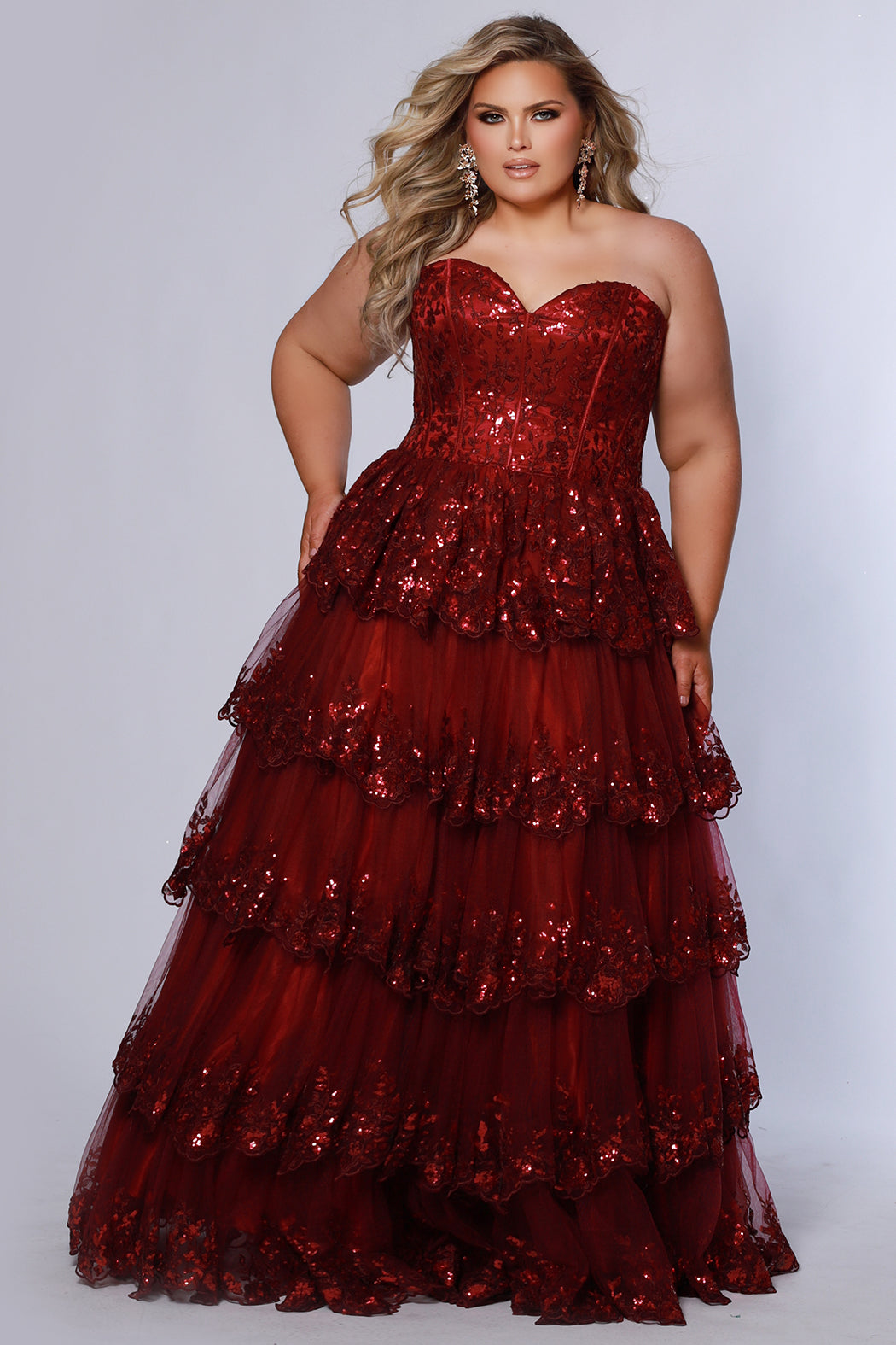Strapless, sweetheart plus size gala formal ballgown. Exposed corset boning on bodice covered in lace applqiues. Tiered A-line skirt with matching lace applique hem. Style SC7398 is available in forest green, navy blue or burgundy red by Sydney's Closet. 