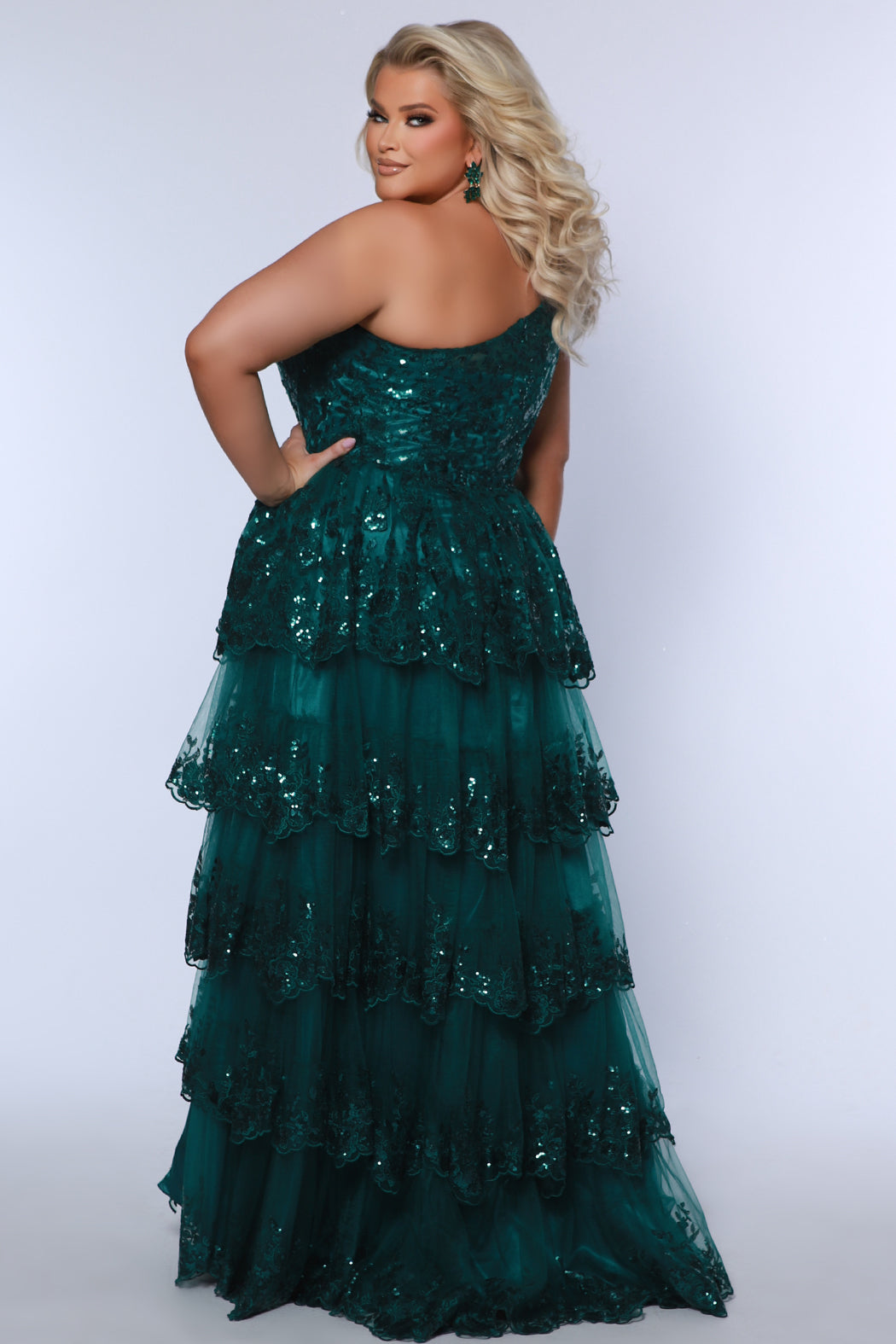 Plus size one-shoulder formal gala Mardi Gras gown with embroidered sequin lace appliques on bodice and on tiered A-line skirt with slit. Available in forest green. navy blue and burgundy red. Style SC7399 by Sydney's Closet. 
