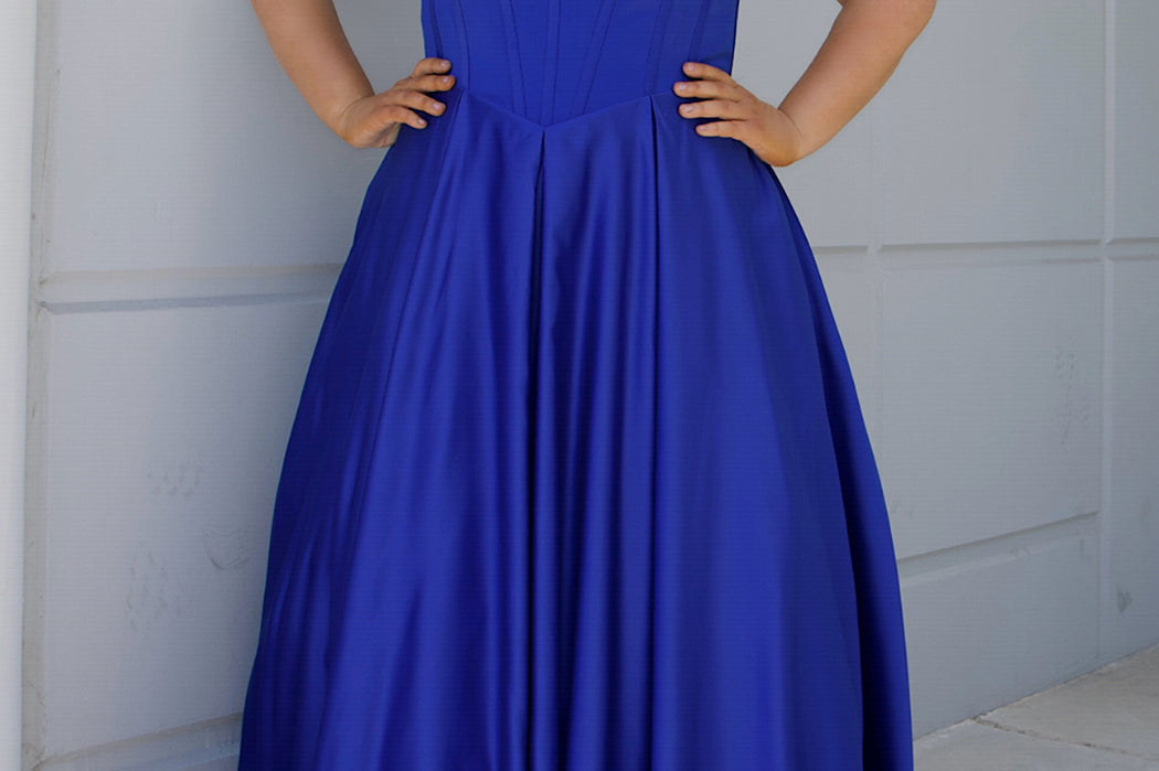 Long formal satin ballgown style SC7400 by Sydney's Closet. Available in sizes 14-32 in colors cobalt blue, onyx black and ruby red.  Pleated bodice with exposed boning, detachable pleated drape sleeves, basque waist and pockets.  