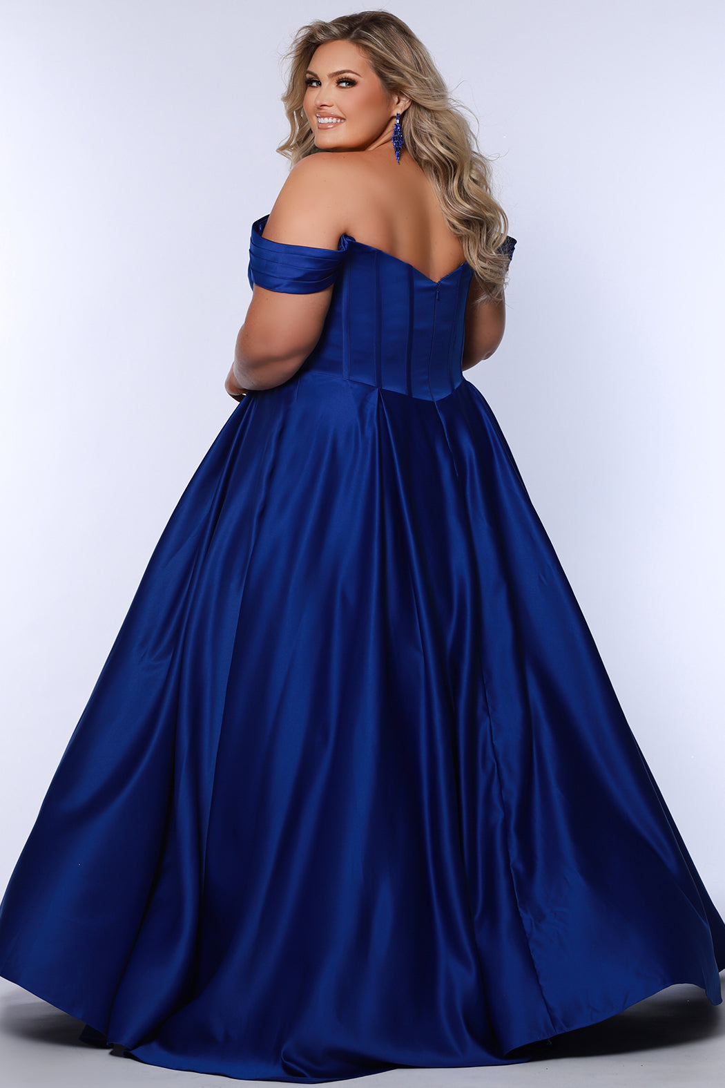 Long formal satin ballgown style SC7400 by Sydney's Closet. Available in sizes 14-32 in colors cobalt blue, onyx black and ruby red.  Pleated bodice with exposed boning, detachable pleated drape sleeves, basque waist and pockets.  