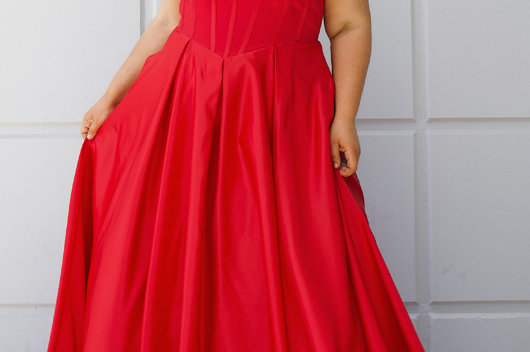 Long formal satin ballgown style SC7400 by Sydney's Closet. Available in sizes 14-32 in colors cobalt blue, onyx black and ruby red.  Pleated bodice with exposed boning, detachable pleated drape sleeves, basque waist and pockets.  