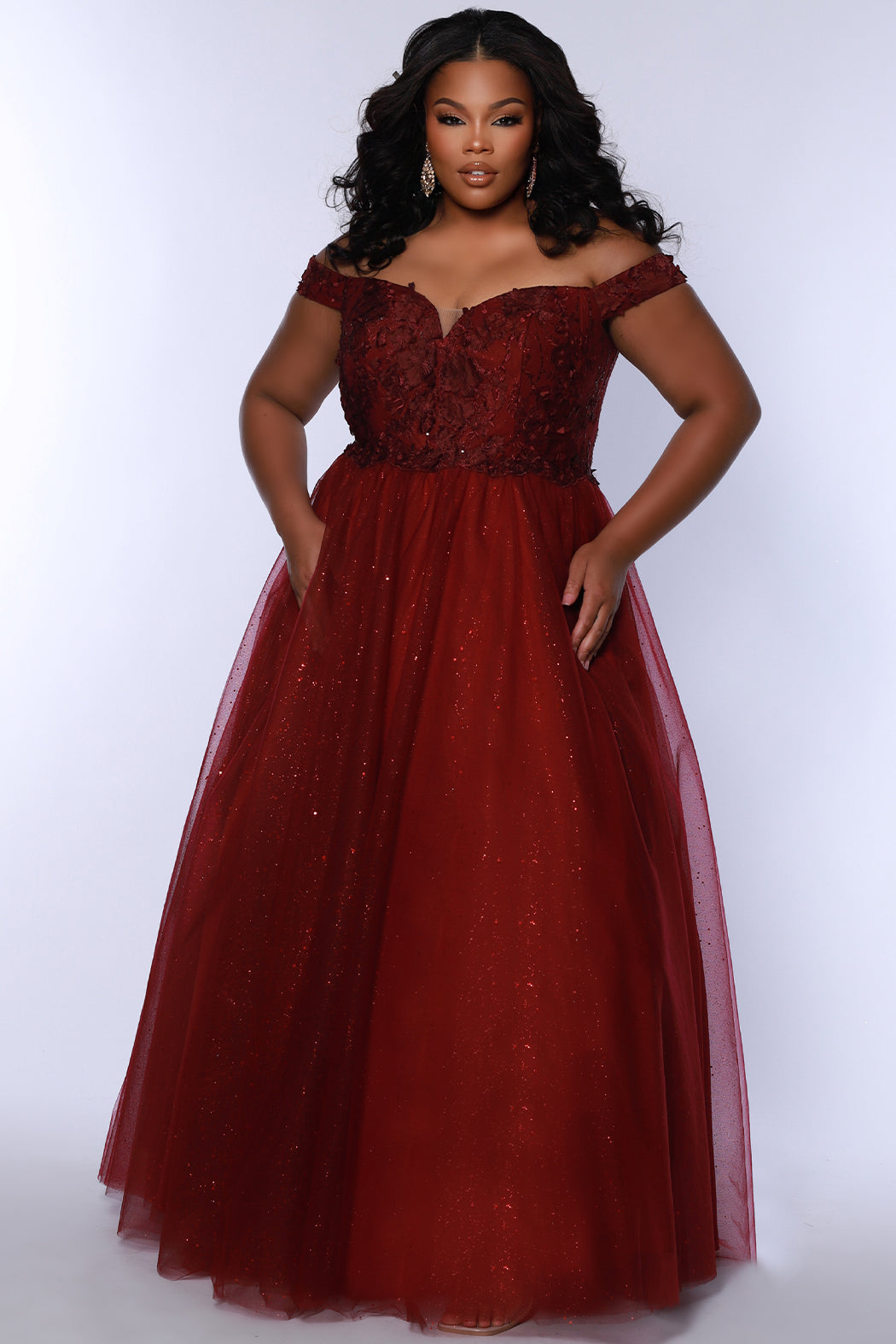Plus size elegeant off-the-shoulder ball gown with 3D floral lace and sparkle tulle. Full A-line skirt and center back zipper. Availablie in burgundy red, onyx black and plum purple in plus sizes 14-40. Style SC7428 from Sydney's Closet.