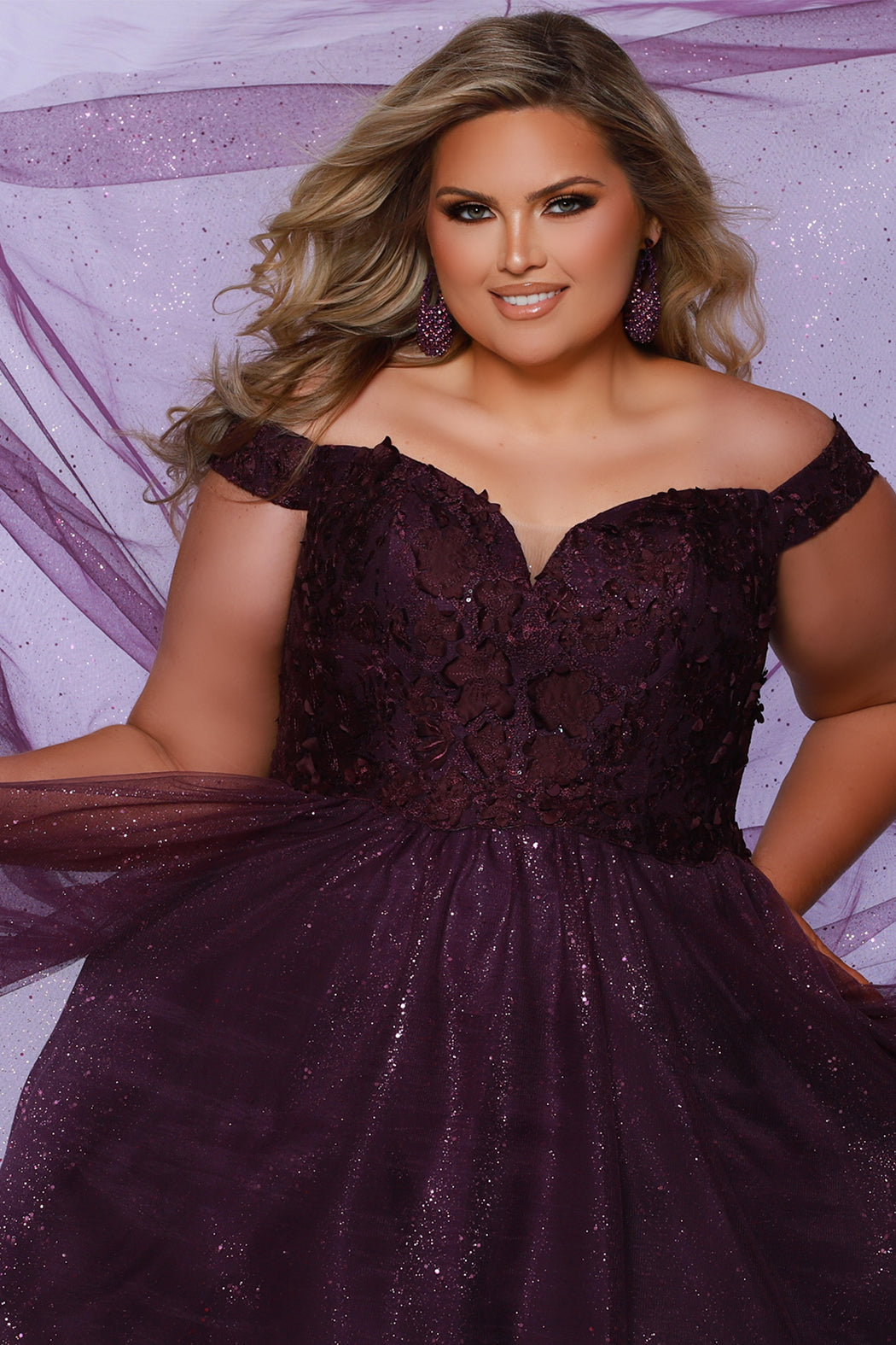 Plus size elegeant off-the-shoulder ball gown with 3D floral lace and sparkle tulle. Full A-line skirt and center back zipper. Availablie in burgundy red, onyx black and plum purple in plus sizes 14-40. Style SC7428 from Sydney's Closet.