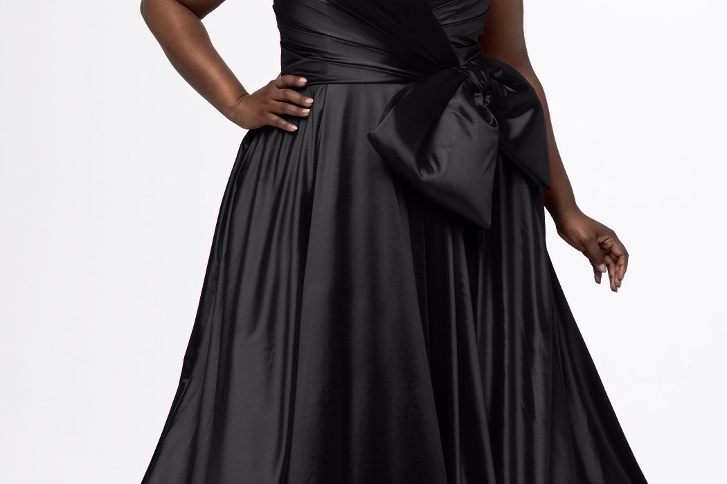 Sydney's Closet style SC7437 in black. 

Plus size A-line formal dress with strapless, pleated bodice, natural waistline with detachable oversized bow, A-line skirt with horsehair hem in silky satin fabric.