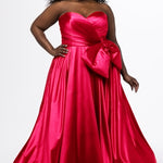 Sydney's Closet style SC7437 in pink. 

Plus size A-line formal dress with strapless, pleated bodice, natural waistline with detachable oversized bow, A-line skirt with horsehair hem in silky satin fabric.
