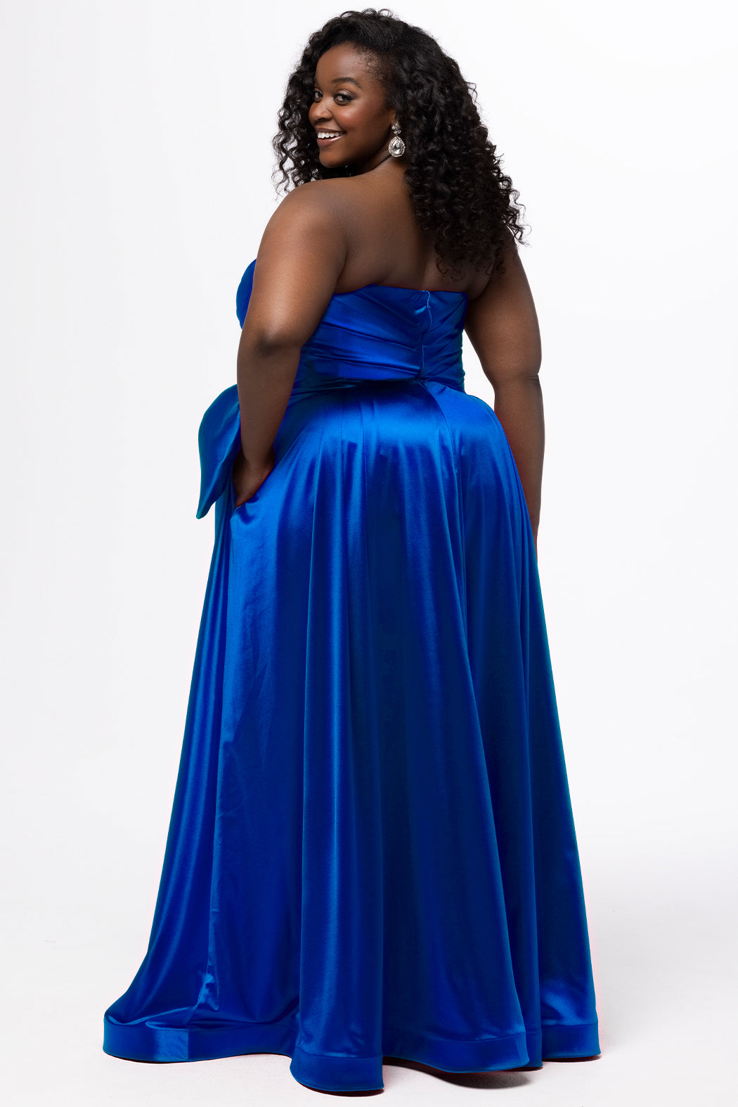 Sydney's Closet style SC7437 in royal blue. 

Plus size A-line formal dress with strapless, pleated bodice, natural waistline with detachable oversized bow, A-line skirt with horsehair hem in silky satin fabric.