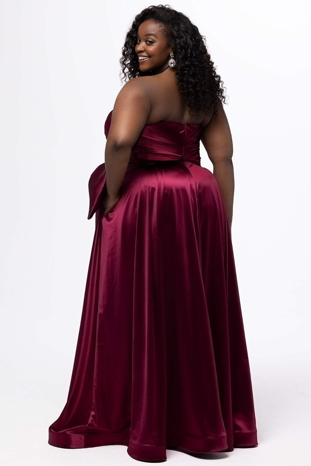 Sydney's Closet style SC7437 in wine. 

Plus size A-line formal dress with strapless, pleated bodice, natural waistline with detachable oversized bow, A-line skirt with horsehair hem in silky satin fabric.