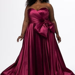Sydney's Closet style SC7437 in wine. 

Plus size A-line formal dress with strapless, pleated bodice, natural waistline with detachable oversized bow, A-line skirt with horsehair hem in silky satin fabric.