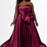 Sydney's Closet style SC7437 in wine. 

Plus size A-line formal dress with strapless, pleated bodice, natural waistline with detachable oversized bow, A-line skirt with horsehair hem in silky satin fabric.