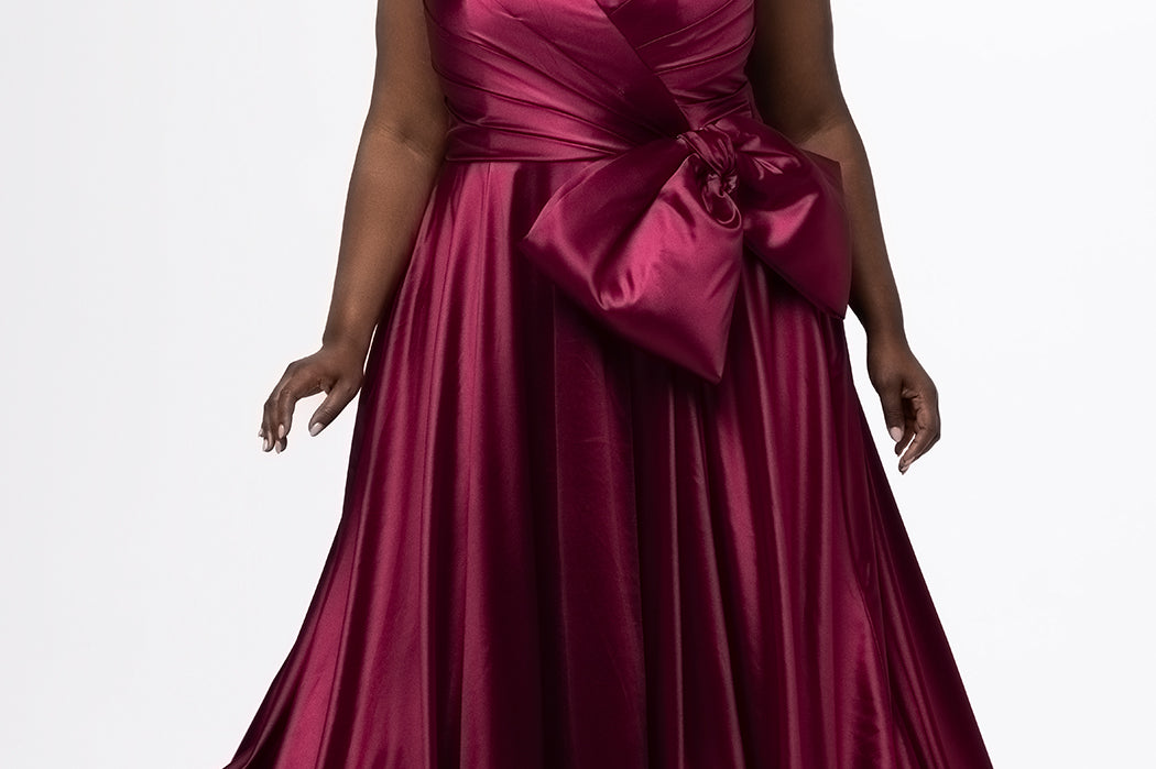 Sydney's Closet style SC7437 in wine. 

Plus size A-line formal dress with strapless, pleated bodice, natural waistline with detachable oversized bow, A-line skirt with horsehair hem in silky satin fabric.