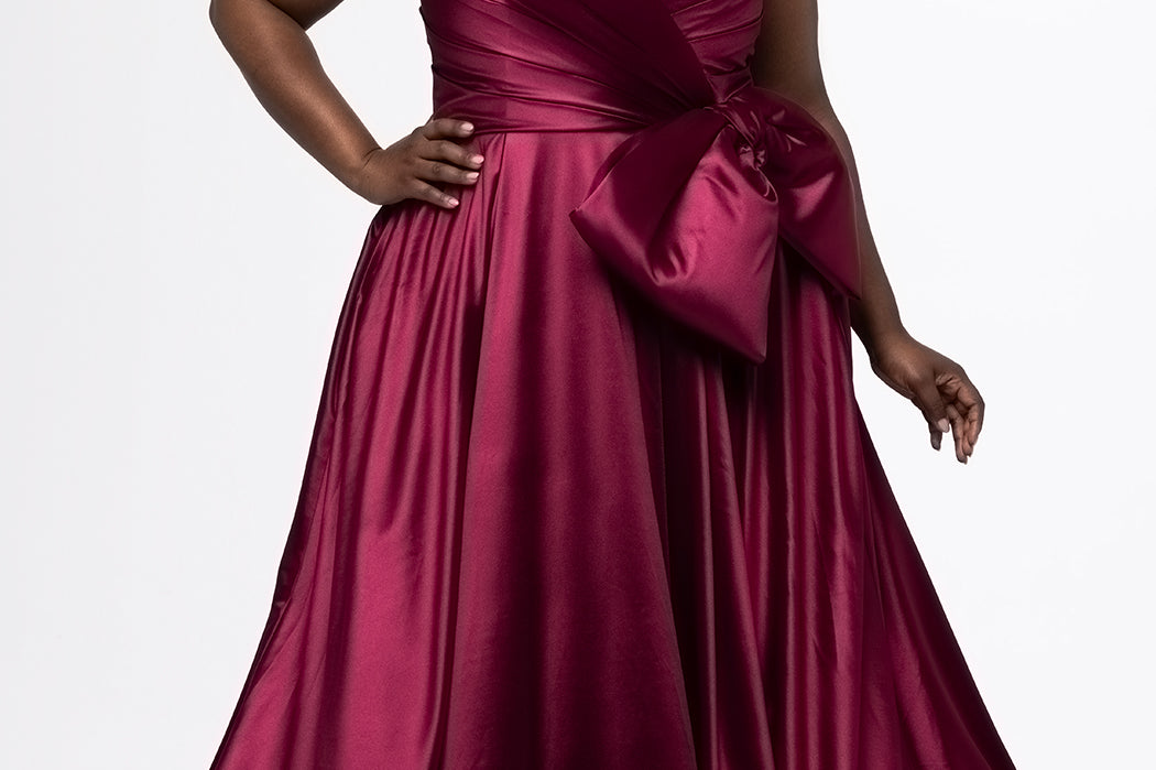 Sydney's Closet style SC7437 in wine. 

Plus size A-line formal dress with strapless, pleated bodice, natural waistline with detachable oversized bow, A-line skirt with horsehair hem in silky satin fabric.
