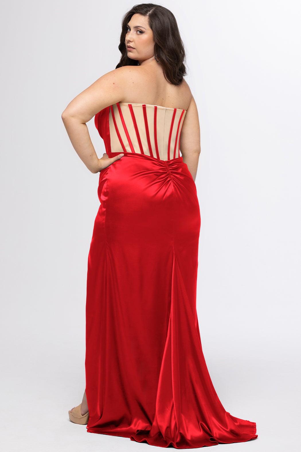 Sydney's Closet style SC7438 in ruby red or ruby red/nude. 

Slim, fitted silhouette with cay eye bodice and hot fix stone detail. Pleated drape over the bust line, exposed corset boning, basque waistline and slim fitted skirt with ruching and slit.  

Choose from tone-on-tone back bodice or color with nude lining on the upper back bodice. 