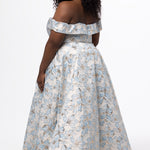 Sydney's Closet SC7440 in light blue floral brocade with gold accents.

Plus size A-line silhouette with off-the-shoulder neckline and fold over cuff on bodice.  Natural waistline with A-line skirt, pockets and left leg slit. 